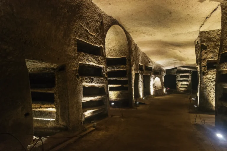 Ancient underground corridors and tombs softly lit inside the Catacombs of San Gennaro during a private guided tour